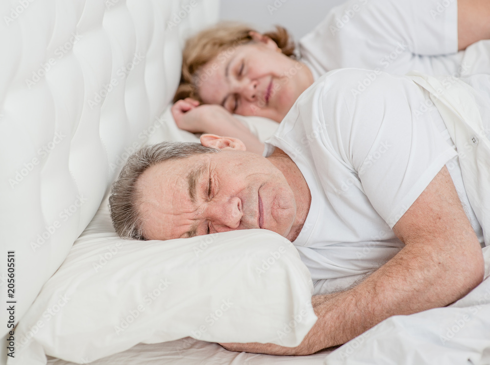 Happy elderly couple sleeping together on the bed Happy elderly couple sleeping together on the bed
