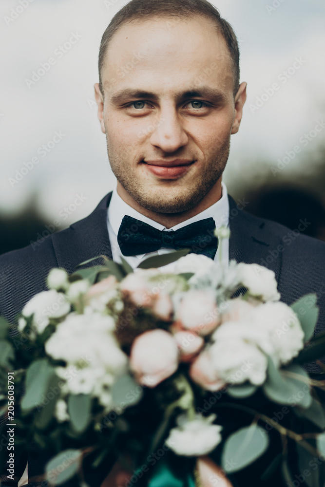 stylish groom portrait with modern bouquet in the morning, wedding ceremony with. luxury man in suit with bow tie and happy look posing. space for text stylish groom portrait with modern bouquet in the morning, wedding ceremony with. luxury man in suit with bow tie and happy look posing. space for text