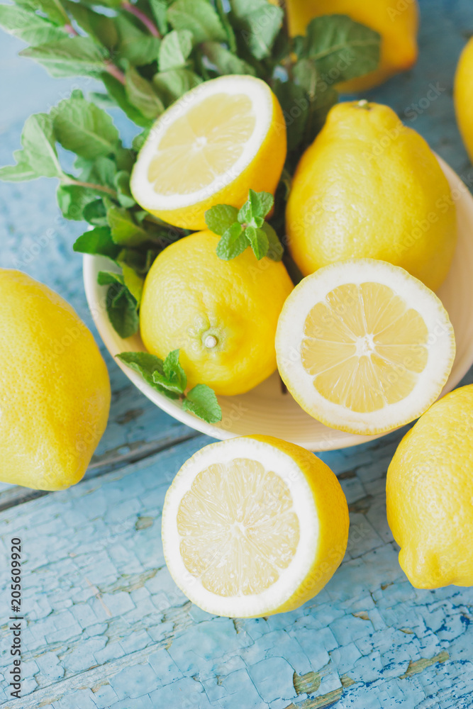 Yellow lemons with mint leaves, wooden background Yellow lemons with mint leaves, wooden background