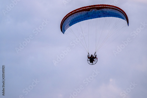 Paraglider flying with paramotor during sunset