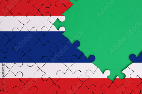 Thailand flag  is depicted on a completed jigsaw puzzle with free green copy space on the right side photo