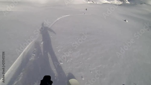 Snowboarder descending the slope of the mountain following another snowboarder photo