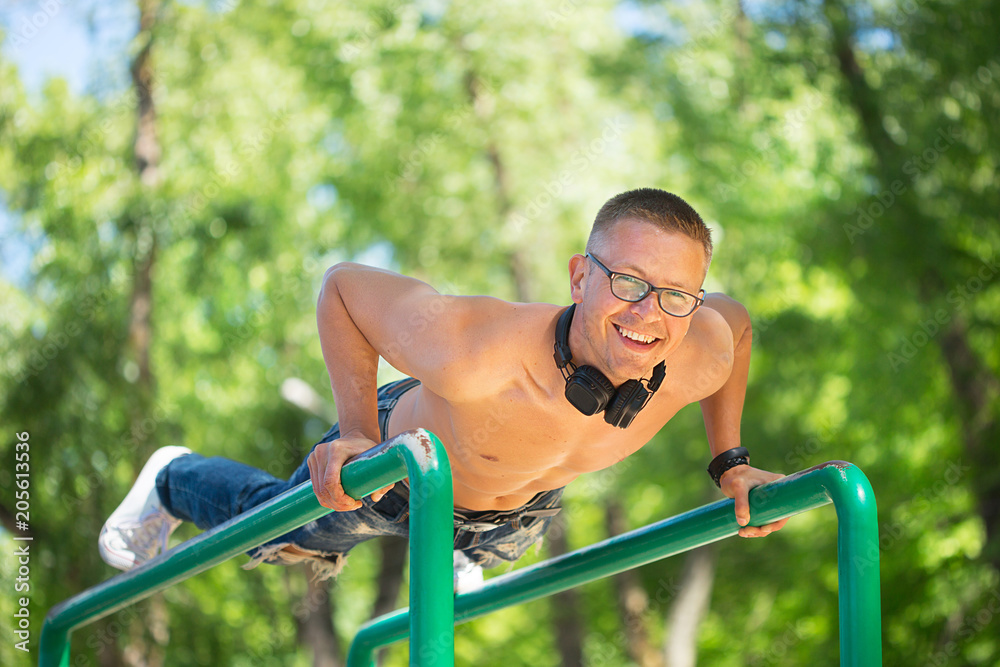 Fototapeta premium A nice sporty man doing outdoor sports in a park with headphones and glasses