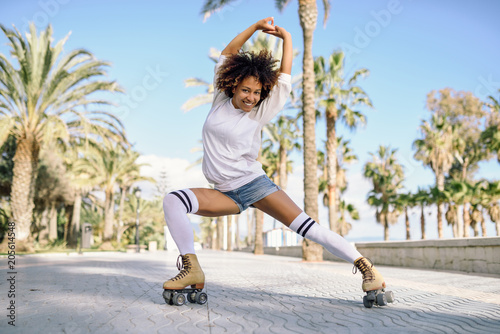 Black woman on roller skates rollerblading in beach promenade with palm trees