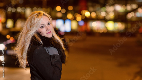 Beautiful, blonde woman in car lights in the night city.