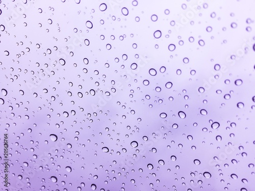 The raindrops on the windscreen or windshield or car glass. View from the inside of the car with a grey sky background. It can be use for texture background or display or backdrop. Adjust the image to