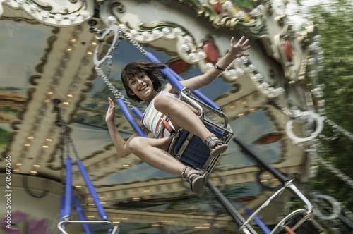 Closeup of exhilarated young girl riding very fast on an amusement park swinging carousel with main subject slightly out of focus to depict speed © David