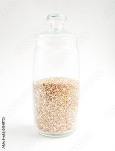 transparent glass container with buckwheat on a light background