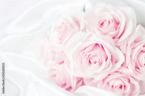 Close up of pink purple rose flowers bouquet on white satin background
