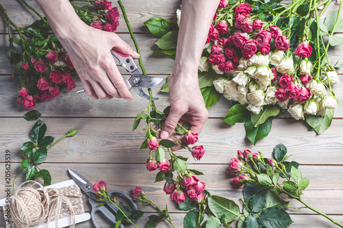 Florist at work. Female hands collect a wedding bouquet of roses. People in the process of work