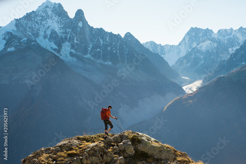 A hiker in the French Alps with the high mountain peaks and glaciers in the distance