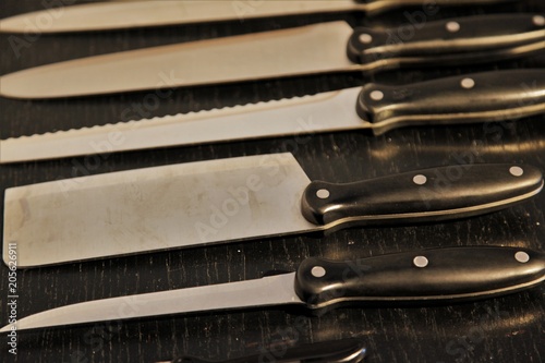 A set of professional kitchen knives on a black table..