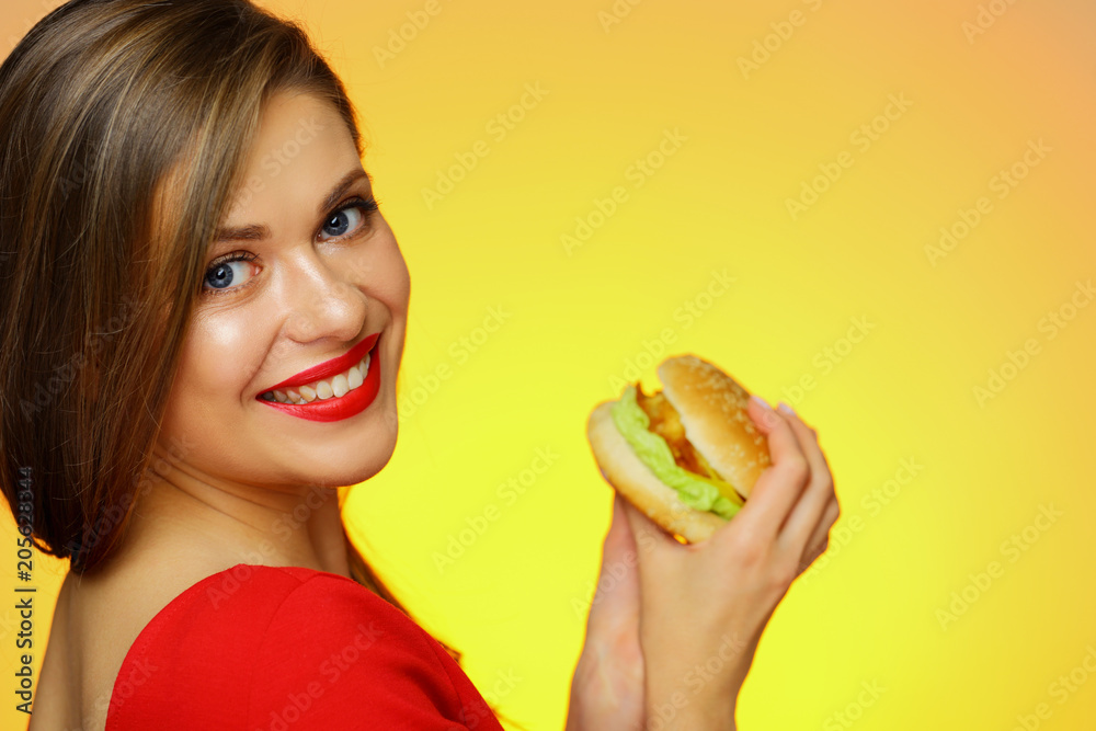 Smiling girl holding burger looks over shoulder. Smiling girl holding burger looks over shoulder.