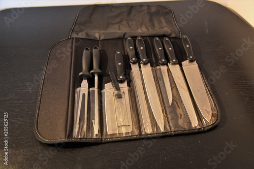 A set of professional kitchen knives on a black table..