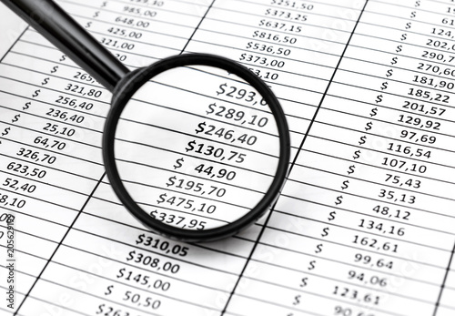Magnifying glass over document with financial data. Business concept.