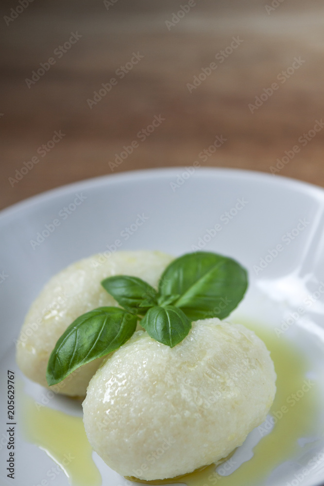 Potato dumplings with meat, butter and fresh basil on a white plate Potato dumplings with meat, butter and fresh basil on a white plate