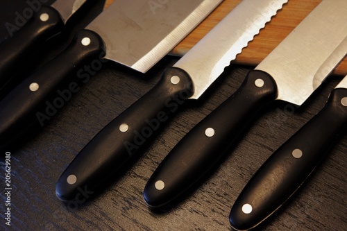 A set of professional kitchen knives on a black table..