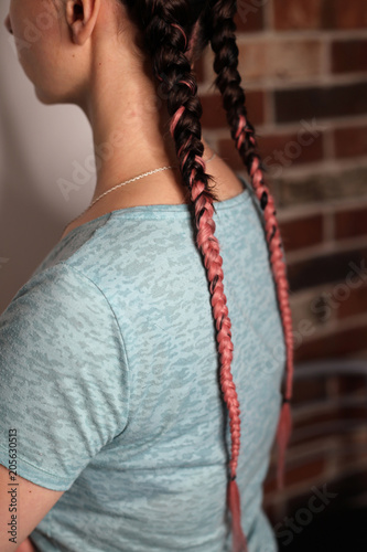 Girl with two braids natural color dirty pink, brown, fashionable youth hairstyle with kanekalon, close-up of the girl's back, thin pigtails photo