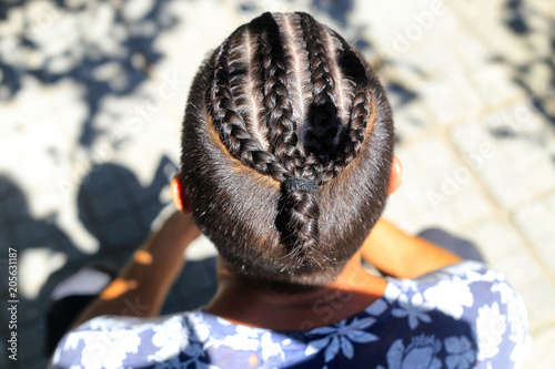 Fototapeta Naklejka Na Ścianę i Meble -  man with a haircut from african braids with a picture of a photo from the top close-up on a neutral background, stylish fashionable young man on a light background