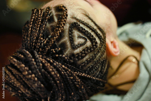thin braids on the head with drawings, African or ethnic style hairstyles on European hair with an interweaving of kanekalon