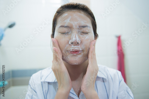 Beautiful young asian woman cleaning face skin with cleansing foam.