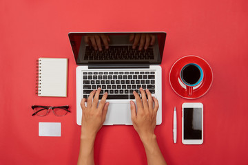 Man hand typing on laptop keyboard with blank screen monitor on red background