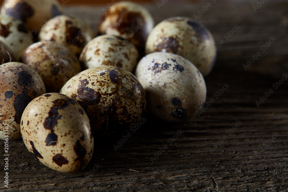 Obraz premium Spotted quail eggs arranged on the background of old wooden boards, with copy-space, selective focus.