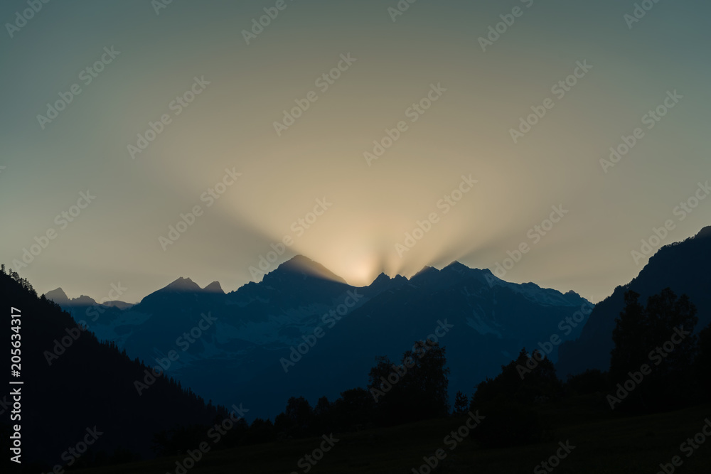 Beautiful sunrise in the morning clear sky with rays and mountain silhouette