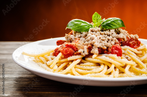 Pasta with meat and tomato sauce on wooden table