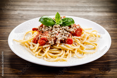 Pasta with meat and tomato sauce on wooden table