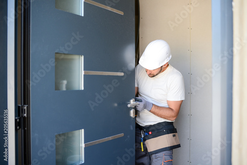 handsome young man installing a door in a new house construction site