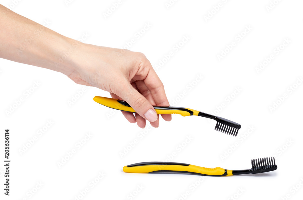 Black and yellow soft toothbrush with hand isolated on white background Black and yellow soft toothbrush with hand isolated on white background