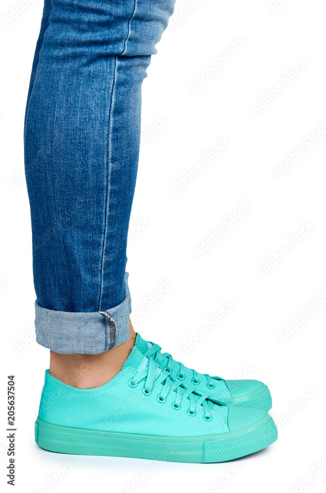 Female leg in jeans and sneakers isolated on white background Female leg in jeans and sneakers isolated on white background