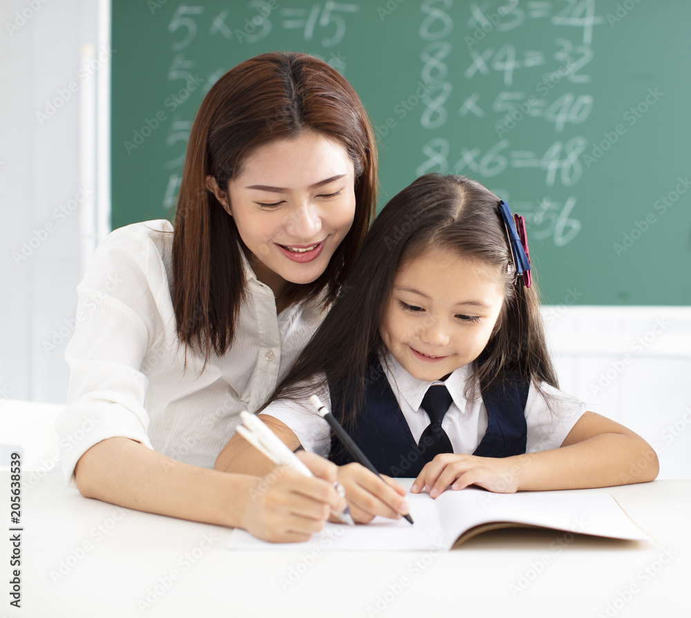 little gile in class writing with teacher helping little gile in class writing with teacher helping