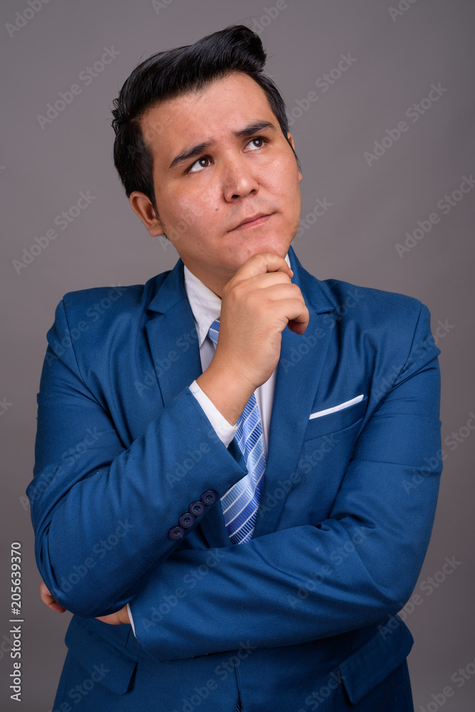 Young multi-ethnic businessman against gray background Young multi-ethnic businessman against gray background
