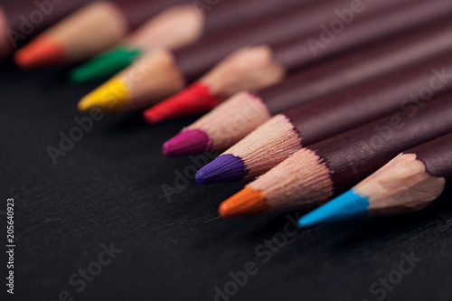 several colored pencils on dark background