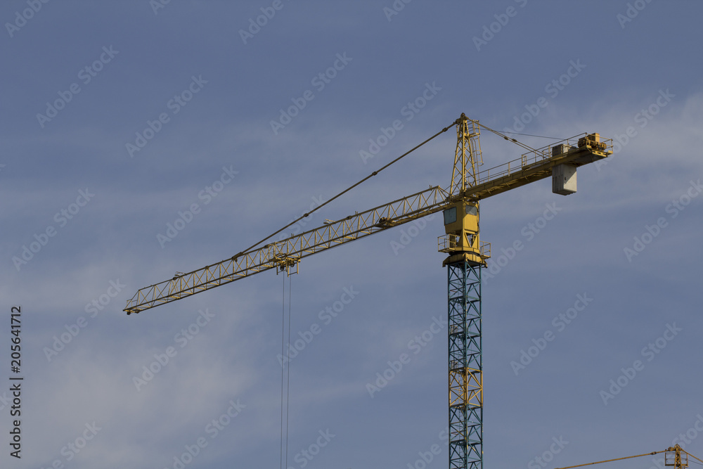 tower crane against the blue sky, the process of building a multi-storey building