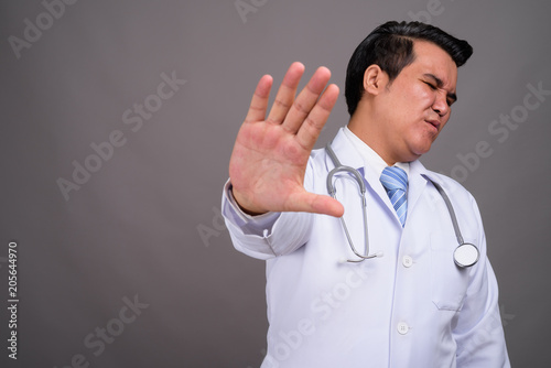 Young multi-ethnic man doctor against gray background