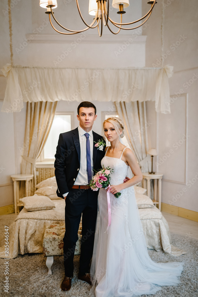 Gorgeous beauty young bride and groom standing indoors in studio or home. portrait woman and man posing in interior.