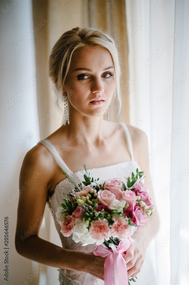 Serious portrait of bride with luxury make-up and hairstyle with a wedding bouquet of flowers, standing in studio indoor photo. Serious portrait of bride with luxury make-up and hairstyle with a wedding bouquet of flowers, standing in studio indoor photo.