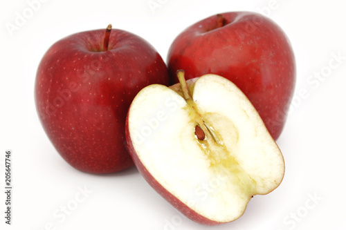 Dos manzanas rojas enteras, sujetan media manzana, partida a la mitad, sobre f