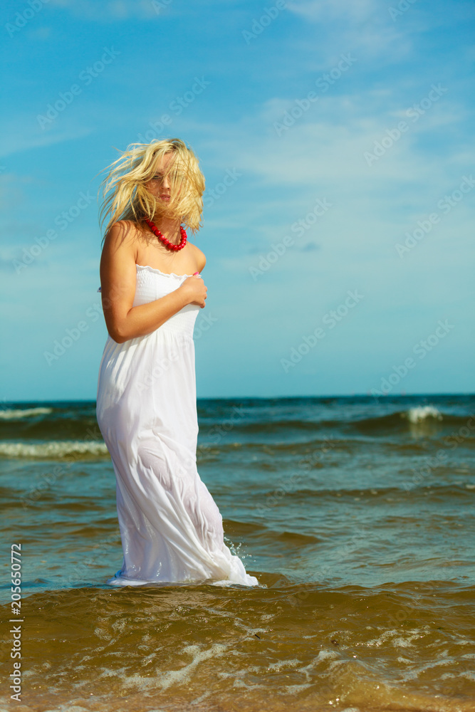 Blonde woman wearing dress walking in water Blonde woman wearing dress walking in water