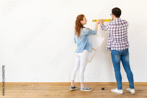 Couple in empty apartment measuring walls. Activities after relocation and renovation.