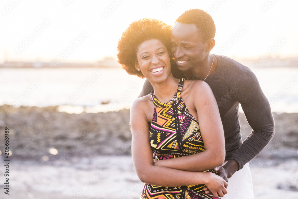 black race african afroamerican couple in relationship or partnership or friendship touching and enjoying the sunset on the beach in vacation outdoor leisure time - obrazy, fototapety, plakaty 