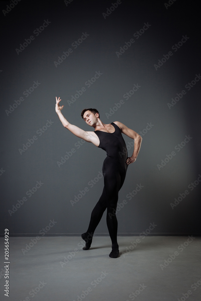Handsome graceful dancer standing and holding up his hand.