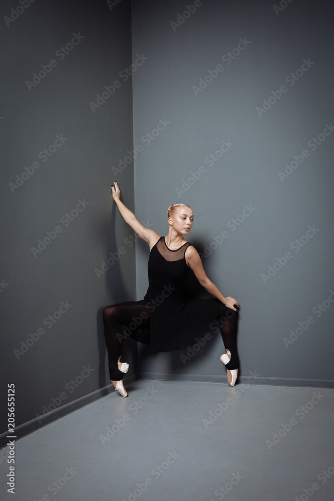 Young cute ballerina sitting down and holding up hand.