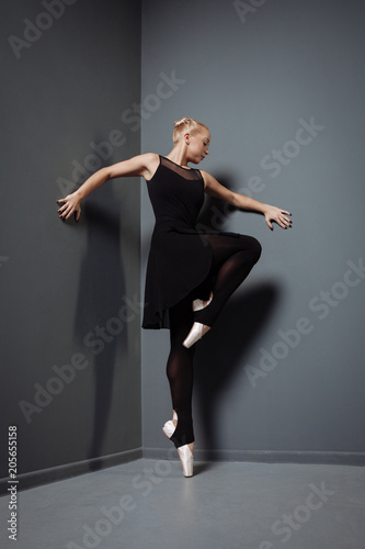 Graceful pretty dancer standing and bending right leg.