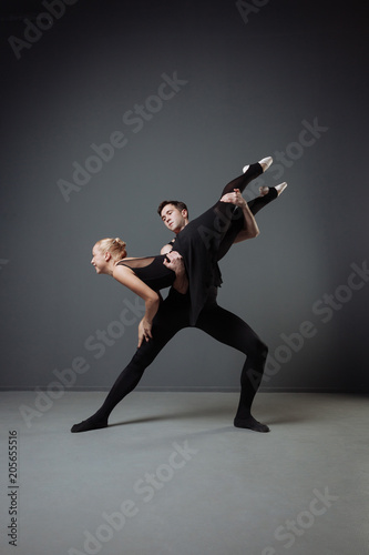 Strong handsome man dancing with ballerina and supporting her.