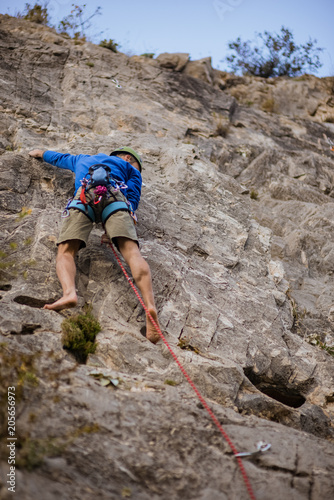 Young man lead climbing on cliff barefoot