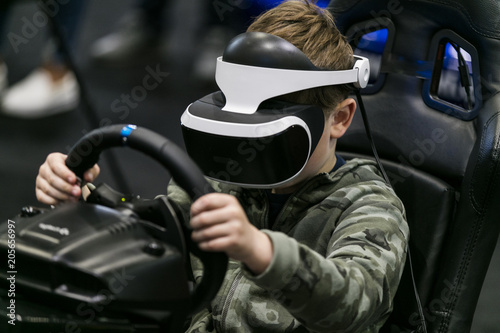 A boy wearing a Virtual Reality headset plays a racing game